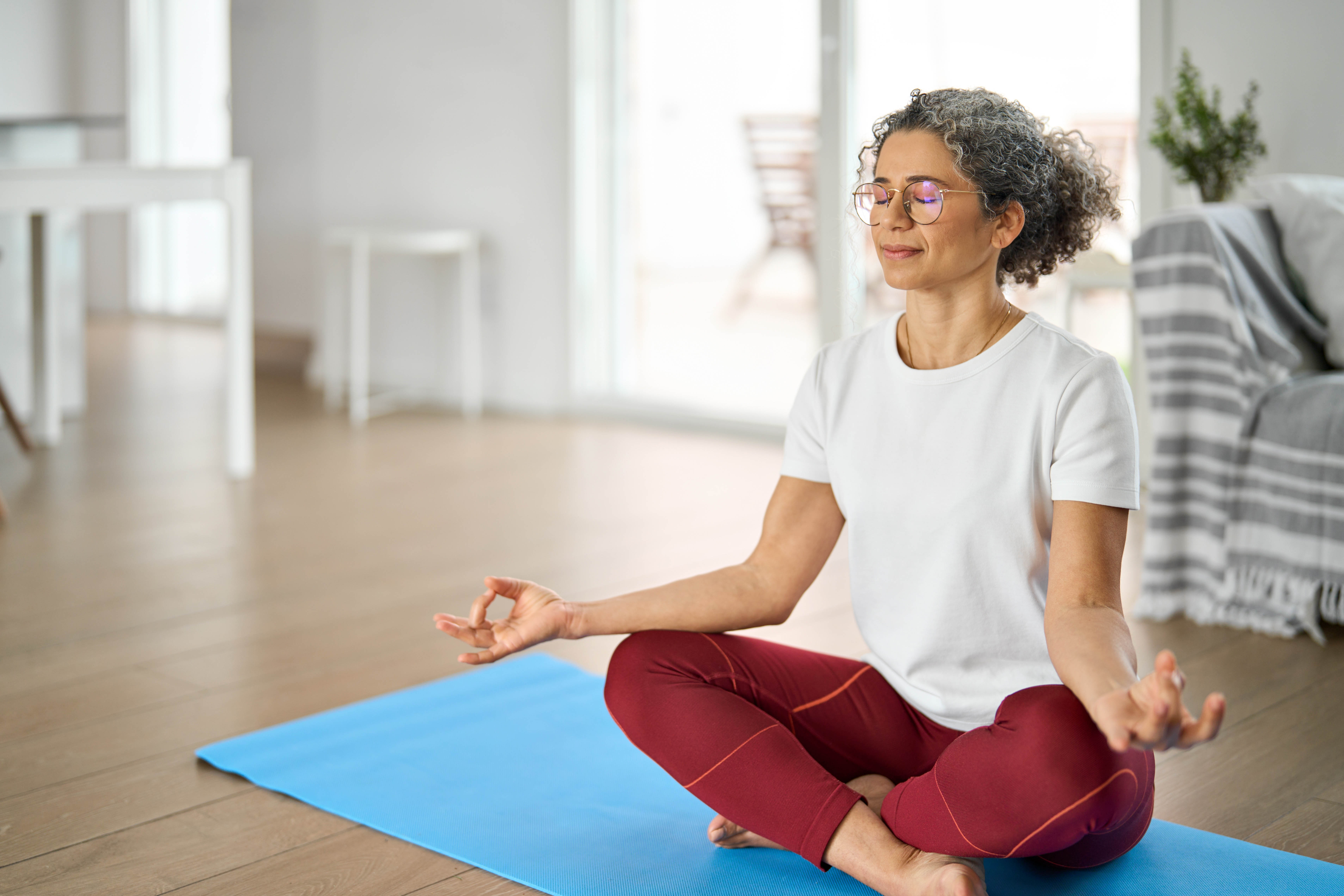 Middle aged woman doing yoga and meditating at home